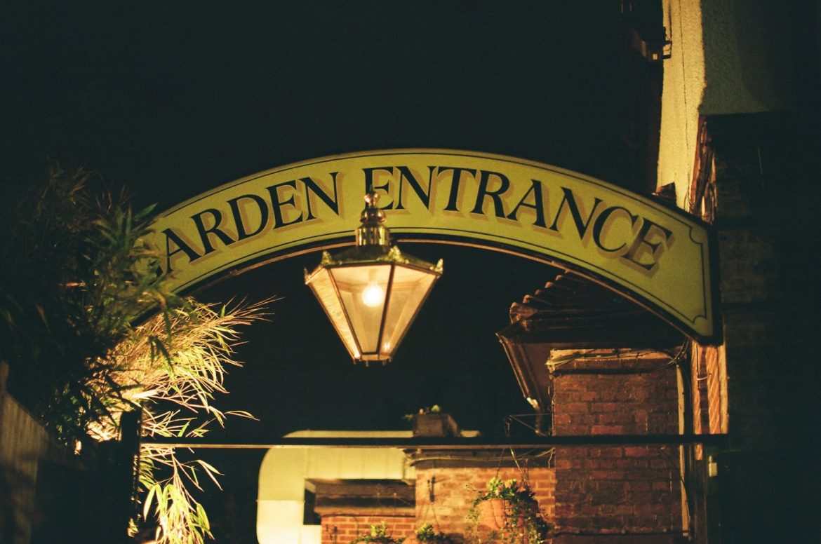 Garden entrance sign with lantern at night