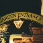 Garden entrance sign with lantern at night